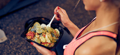 A woman eating a healthy meal at the gym
