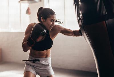 A woman punching a punching bag with boxing gloves on
